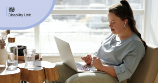 A disabled woman sits with a laptop in a light bright office. In the corner of the image, it says 'Disability Unit' on a light purple background.