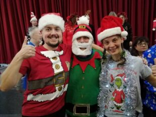 Three individuals dressed up in Christmas outfits. 